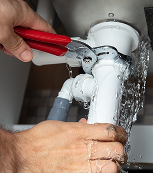 plumber turning off a leaking pipe
